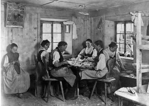 Durch die Erweiterung des Museums wird Platz für die Ausstellung von Holzspielzeug geschaffen; die historische Aufnahme zeigt Spielzeugschnitzer und -schnitzerinnen in der Stube eines Bauernhauses in Wolkenstein, La Pozza, um 1905.